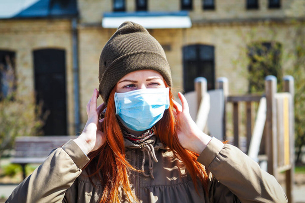 通りに生姜色の髪を持つ美しい若いヨーロッパの女性は、上の医療面マスクで。人工呼吸器の若い女性の閉鎖は、コロナウイルス感染から保護するために- Covi19 - 写真・画像