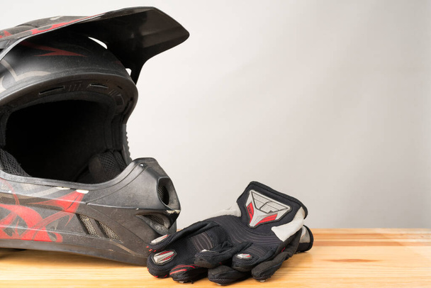 Motocykl ochronny - kask motocross i rękawiczki na drewnianym tle. Przestrzeń kopiowania po prawej. - Zdjęcie, obraz