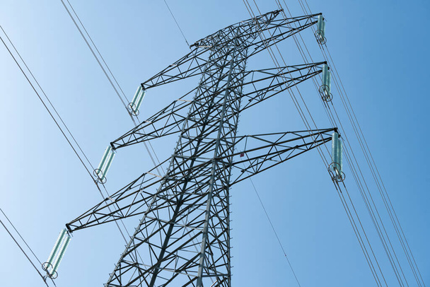 Linee elettriche aeree su una torre di trasmissione sullo sfondo del cielo blu. Concetto di distribuzione elettrica
. - Foto, immagini
