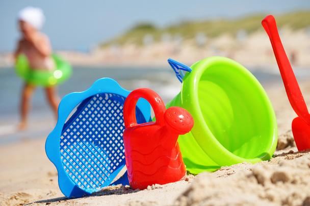 Пластиковые детские игрушки на песчаном пляже
 - Фото, изображение