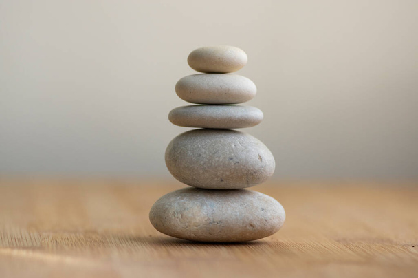 Stone cairn on striped grey white background, five stones tower, simple poise stones, simplicity harmony and balance, rock zen sculpture - Foto, Bild