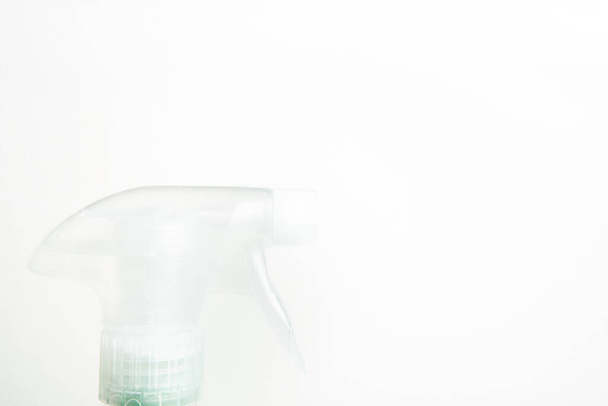 Eine Nahaufnahme des oberen Teils einer transparenten Sprühflasche aus Kunststoff auf einem schlichten weißen Hintergrund. - Foto, Bild