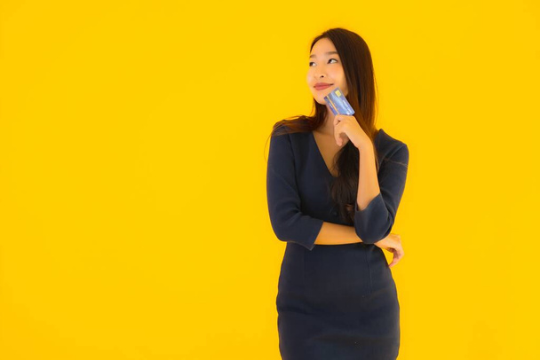 Portrait belle jeune femme asiatique avec carte de crédit sur fond jaune isolé
 - Photo, image