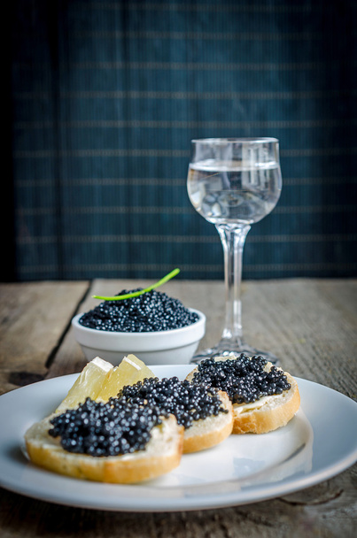 Sandwiches with black caviar and glass of vodka - Photo, Image