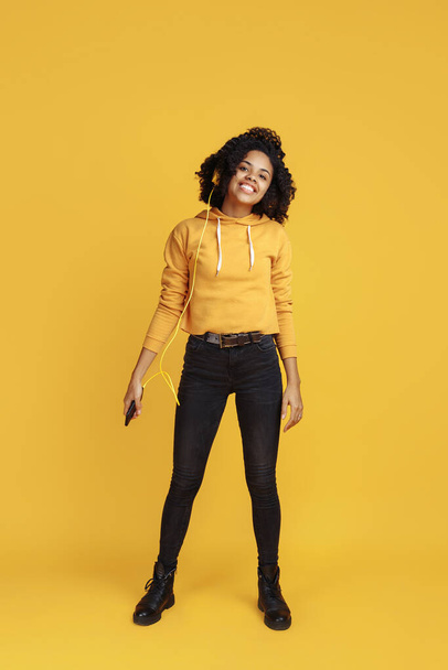 Full lengh image of positive african american young woman dressed in casual clothes over yellow background. - Foto, Imagem