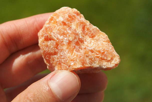 Orange Calcite mineral from  Brazil held in a hand - Valokuva, kuva