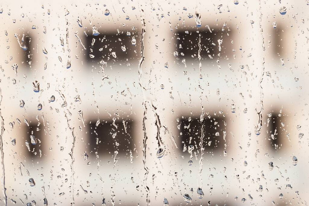 Краплі дощу на віконному склі на фоні будівлі
 - Фото, зображення
