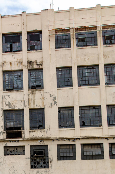 Η πρόσοψη ενός εγκαταλελειμμένου κτιρίου. Σπασμένα παράθυρα και βαφή ξεφλούδισμα - Φωτογραφία, εικόνα