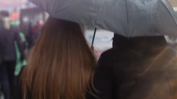 Egy esernyő alatt sétáló pár az utcán. A fiatalok esernyő alatt sétálnak az esőben.. - Felvétel, videó