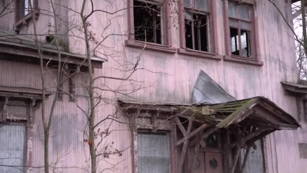 Stary opuszczony dom z wybitymi szybami. Opuszczone stare okno z gałęziami drzew. Różowy dom w ruinie z wybitym oknem - Materiał filmowy, wideo
