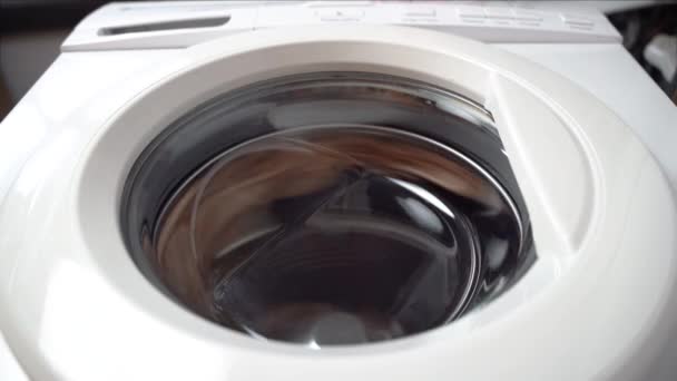 Washing machine finishes spinning and things fall on the glass door. Front view from bottom, an unusual perspective - Footage, Video