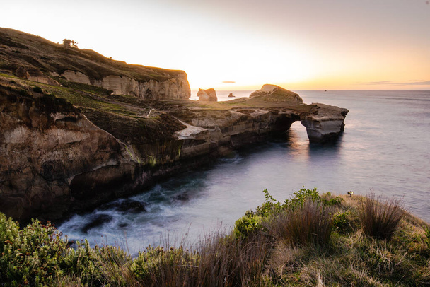 Όμορφη ανατολή με φυσική αψίδα στην παραλία του Τούνελ, χερσόνησος Otago, Νέα Ζηλανδία. - Φωτογραφία, εικόνα