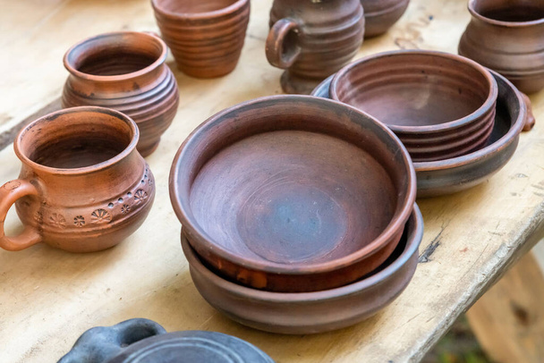 pattern of rustic dishes made of clay a stack of plates and cups on a wooden table - Foto, Imagen