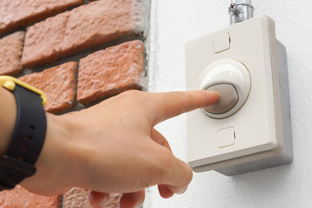 Hand pressing a doorbell switch on the wall - Photo, Image