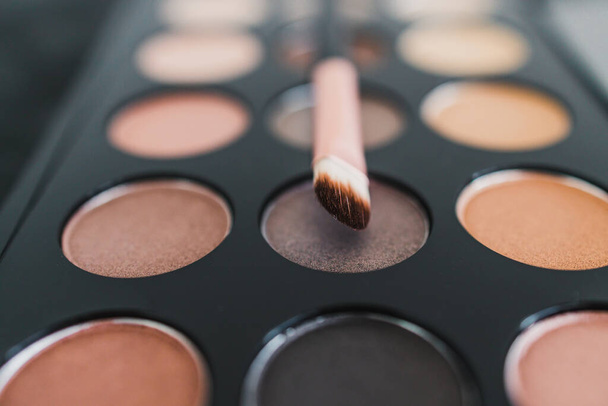 cosmetics and beauty industry concept, close-up of eyeshadow palette with neutral nude tones and brush on it  - Foto, Imagen
