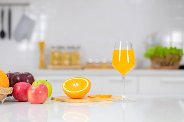 Appelsiinimehu sijoitetaan valkoiselle pöydälle, appelsiinimehu, kirkkaat värit pöydälle ja ilmapiiri keittiössä on puhdas valkoinen.. - Valokuva, kuva