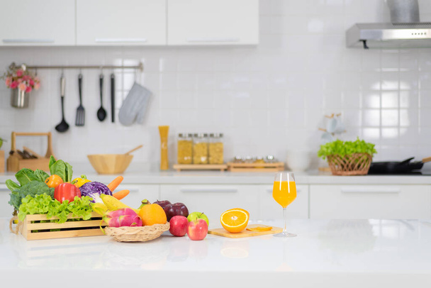 Sinaasappelsap wordt geplaatst op een witte tafel, sinaasappelsap, felle kleuren op de tafel en de sfeer in de keuken is schoon wit. - Foto, afbeelding