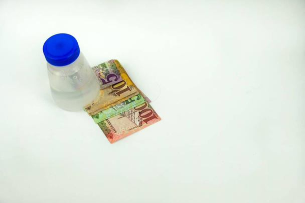 Imagem isolada de notas de banco saudi riyal em SAR5, 10, 50 e 100 denominação sob garrafa de plástico sobre branco. Foco em textos de denominação em notas SAR 100
 . - Foto, Imagem