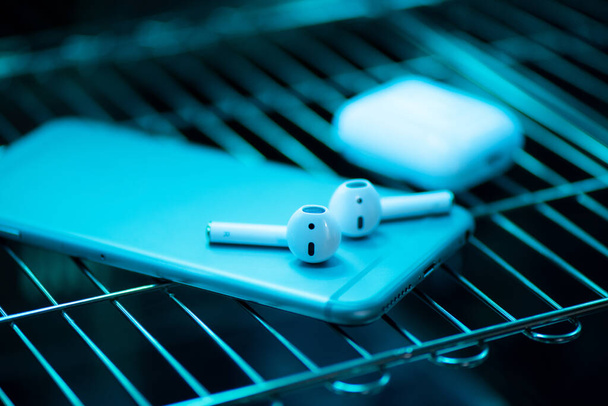 UV light sterilization of smartphone and earbuds. COVID-19 prevention concept. - Photo, Image