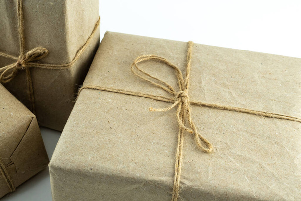 κουτί δώρου σε καφέ συσκευασία με κορδέλα γιούτα σε λευκό φόντο - Φωτογραφία, εικόνα