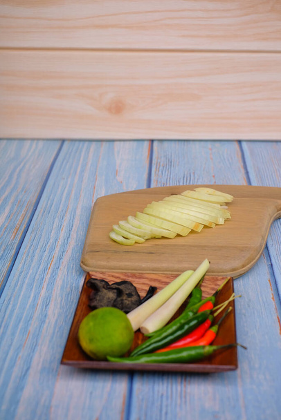 Planche à découper en bois avec sel, msg, gingembre, ail, oignon, citron vert, piments et citronnelle sur le fond en bois
. - Photo, image