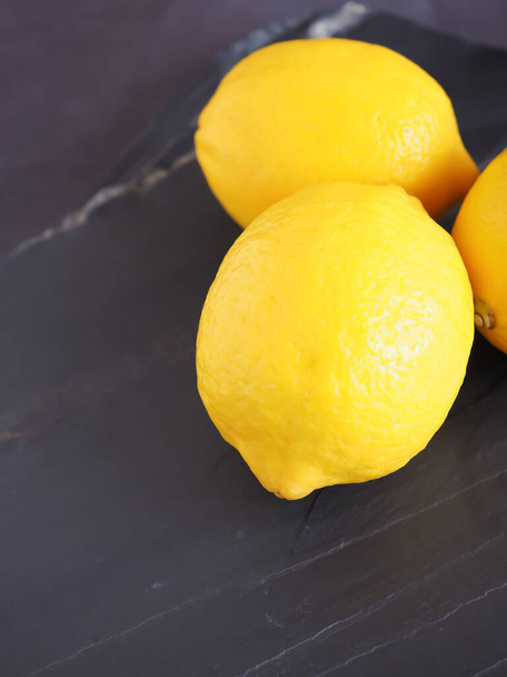 Chiudi frutta al limone su uno sfondo di pietra nera, Alta vitamina C, che aiuta a controllare il peso e ridurre il rischio di cancro. Copia spazio per testo
 - Foto, immagini