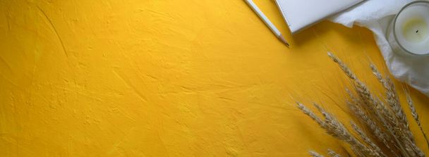 黄色のコンクリートの背景に文房具、キャンドル、装飾やコピースペースと創造的なワークスペースのトップビュー - 写真・画像