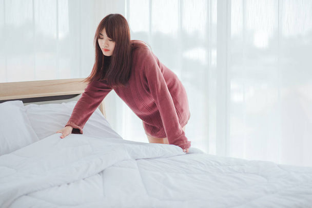 Frauen ordnen Bettwäsche auf dem Bett im Zimmer. - Foto, Bild