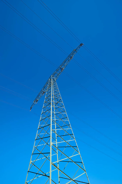   Power pole on a field under a cloudless blue sky                              - Photo, Image