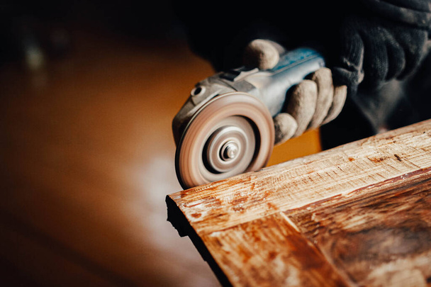 woodwork, a grinder cuts old paint and varnish from a solid wood board. furniture restoration. - Zdjęcie, obraz