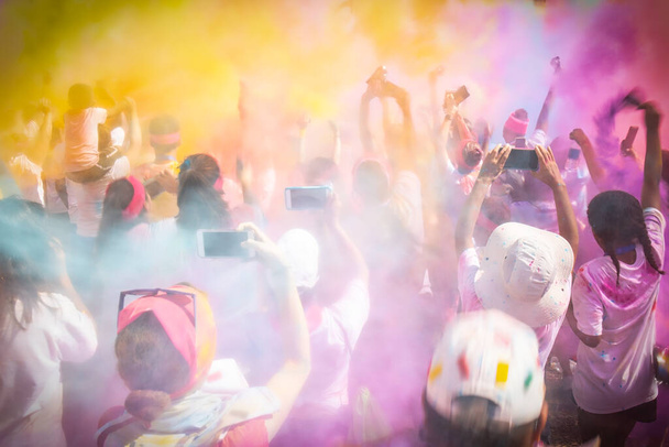 Ένα ενθουσιασμένο πλήθος γιορτάζει πετώντας χρωματιστή σκόνη στον αέρα. - Φωτογραφία, εικόνα