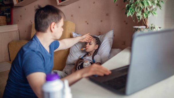 Orta yaşlı bir baba dizüstü bilgisayar ekranına bakıyor ve evdeki bir doktora danışıyor tecrit sırasında tele-sağlık hizmetleri, uzak video görüşmeleri, modern teknoloji sağlık uygulamaları... - Fotoğraf, Görsel