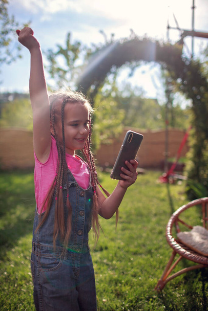 Élégant 7-8 ans fille bavarder avec des amis avec smartphone et amusez-vous avec des jeux d'attrapage avec des effets de caméra de réalité augmentée, jeu virtuel pendant le verrouillage et après, nouvelle amitié normale
 - Photo, image