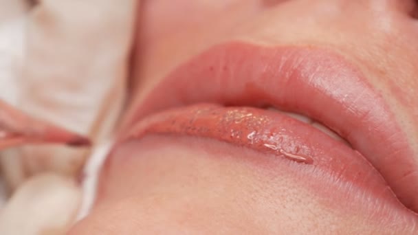 Мікроблокування татуювання губ спеціальним забарвленням червоного пігменту, який виправляє колір губ у клініці косметології. Перманентна процедура макіяжу губ нанесення пігментного макіяжу на губи за допомогою татуювальної машини крупним планом
 - Кадри, відео