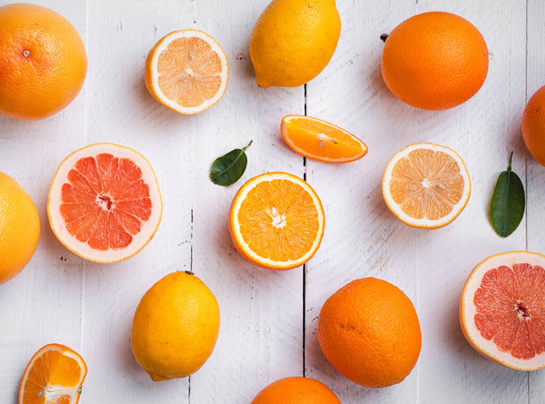 Κομμένα πορτοκάλια, γκρέιπφρουτ, λεμόνι στο ατσάλινο φόντο στο στούντιο - Φωτογραφία, εικόνα