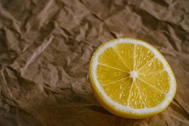 Eine halbe Zitrone auf zerknülltem braunem Papier. - Foto, Bild