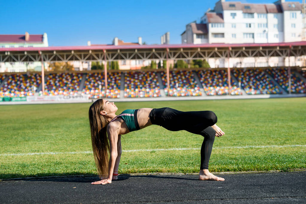 Sporty young woman doing warm up squat, stretching at stadium.   Healthy lifestyle concept - Photo, Image