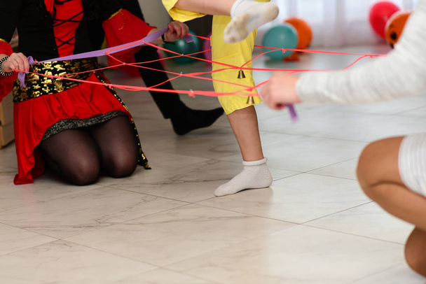 Los niños en una fiesta juegan un juego saltando sobre una cuerda con una campana
. - Foto, imagen