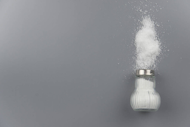 A pile of salt from salt shaker, concept excessive salt intake and white death - Foto, afbeelding