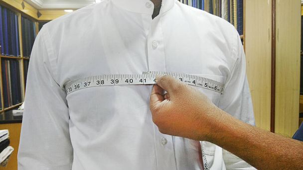 Räätälöinnin lähikuva mittaamalla miehen rintakehä mittanauhalla - Valokuva, kuva