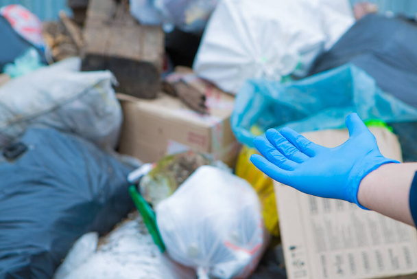 a man in rubber gloves points to a pile of garbage in a container. garbage collapse. Janitors ' strike. environmental disaster of plastic recycling. hand close-up - Φωτογραφία, εικόνα