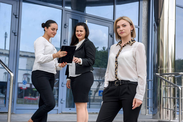Três mulheres de negócios com tablets em pé do lado de fora do edifício e olhando para a câmera - Foto, Imagem