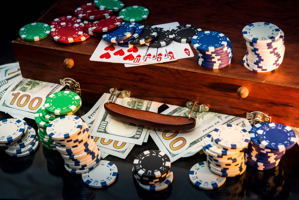 Gokken Concepten. Wedden is een gok voor investeerders. Case vol chips, dollars en speelkaarten op een zwarte achtergrond - Foto, afbeelding