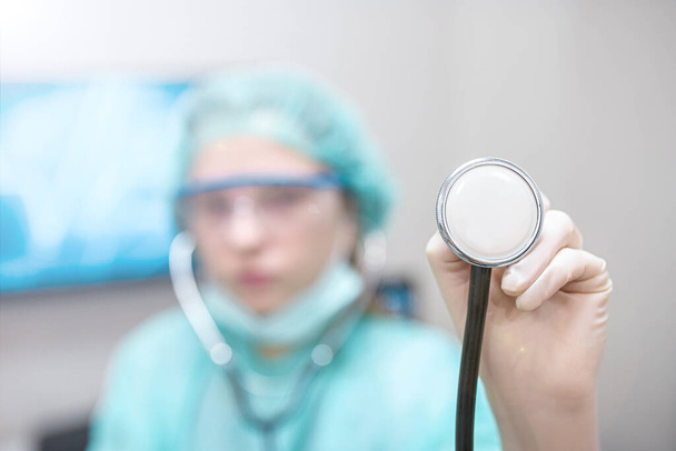 young woman intern doctor in medical mask and uniform using stethoscope - Φωτογραφία, εικόνα