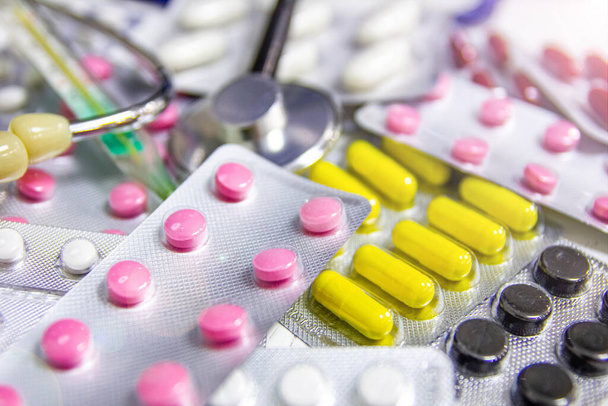 conjunto de comprimidos farmacêuticos coloridos e estetoscópio com termômetro, conceito de diagnóstico médico e terapia
 - Foto, Imagem