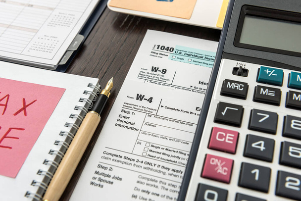 Belastingformulier, pen en rekenmachine aan het bureau. Financiële rekening - Foto, afbeelding