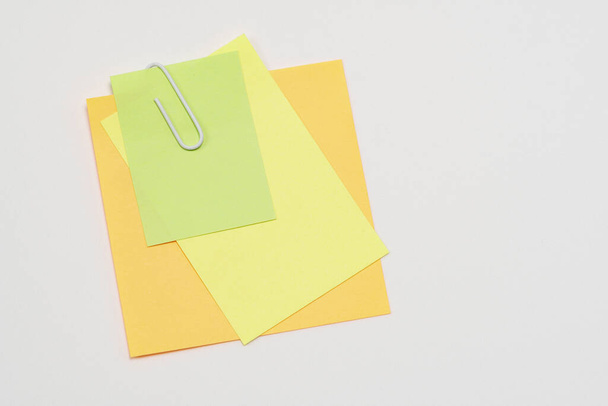 Notas de papel multicolores sujetadas con un clip de papel sobre un fondo blanco. De cerca.
 - Foto, Imagen