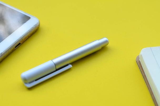  stylus pen and cell phone on yellow background - Photo, Image