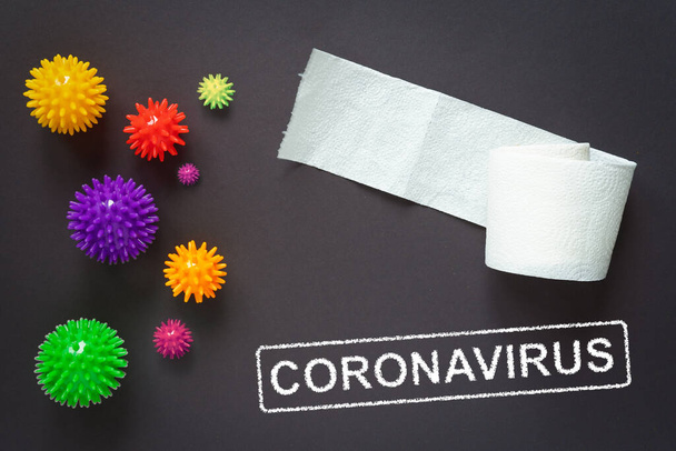 Słowo koronawirusa na szarym tle. Papier toaletowy na stole. Covid-19 w postaci kulek z igłami. Koncepcja epidemii. - Zdjęcie, obraz