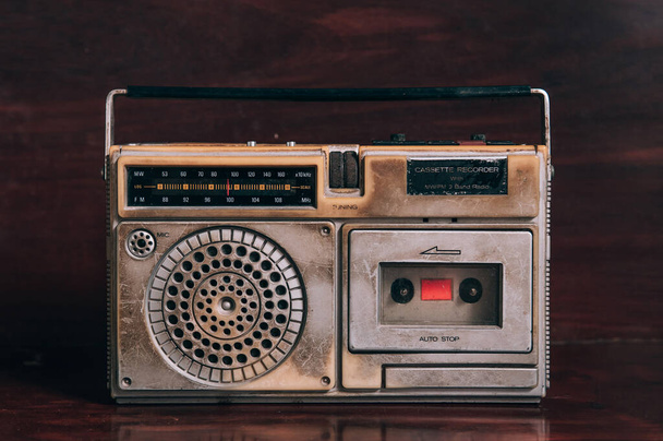 Старый винтажный деревенский транзисторный радио с кассетным магнитофоном на темном деревянном фоне
 - Фото, изображение